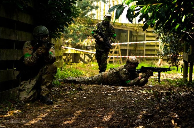 Airsoft players holding a defensive position using cover, one prone with a support weapon